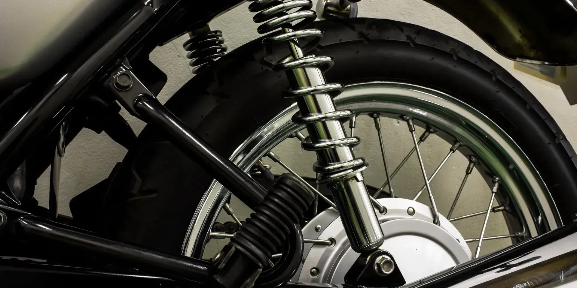 Chrome coil-over rear shock on a motorcycle with a spoked wheel