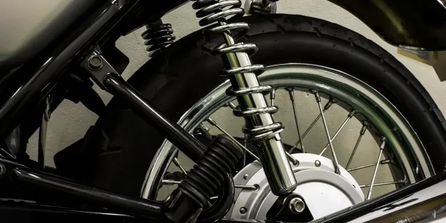 Chrome coil-over rear shock on a motorcycle with a spoked wheel