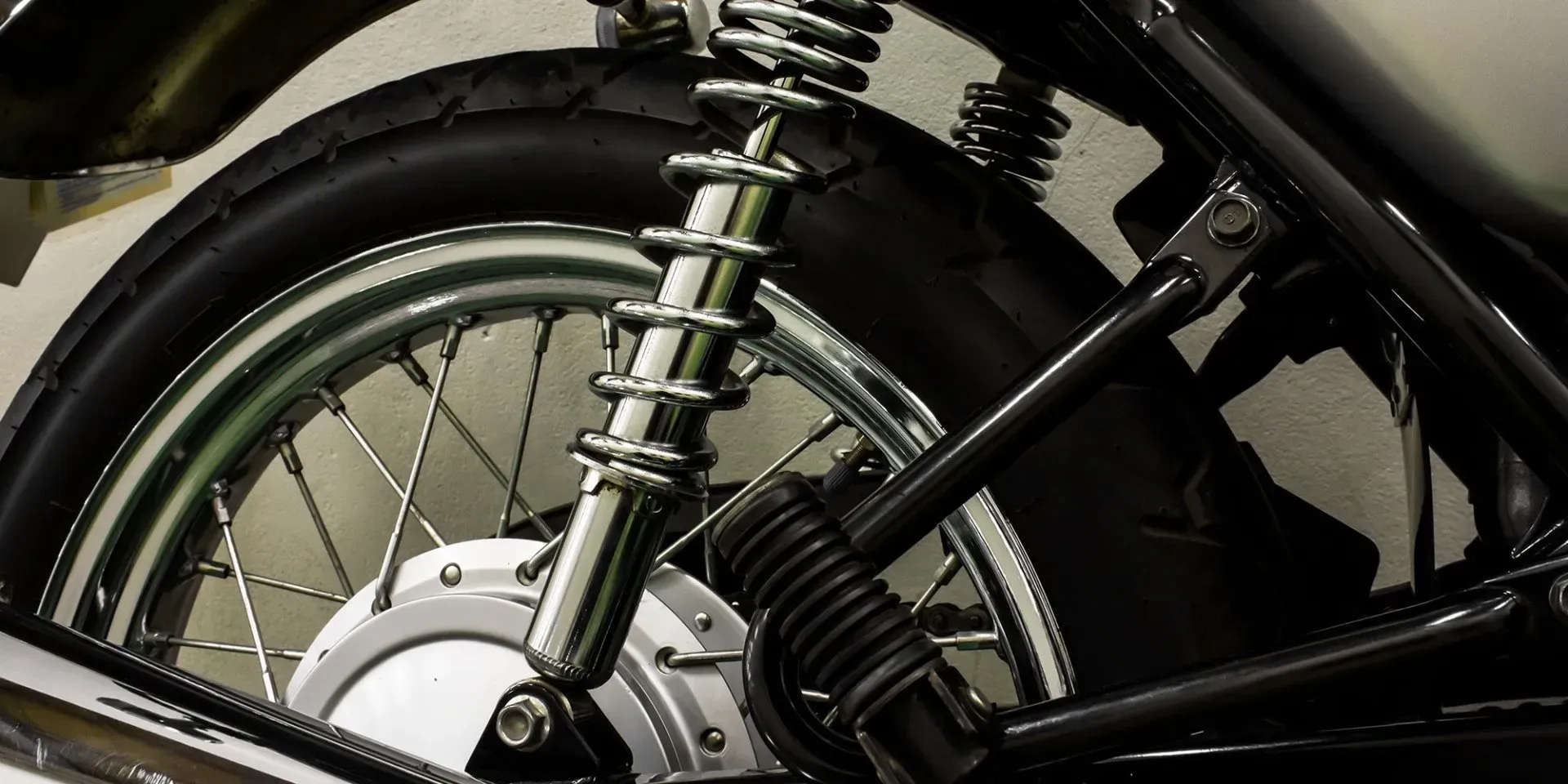 Laced chrome spoked motorcycle wheel beside a coil-over rear shock