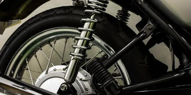 Laced chrome spoked motorcycle wheel beside a coil-over rear shock