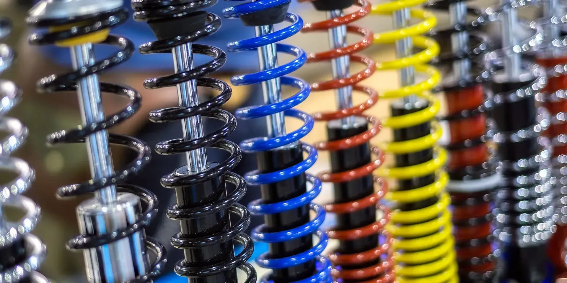 Row of coil-over shock absorbers with black, blue, red and yellow springs