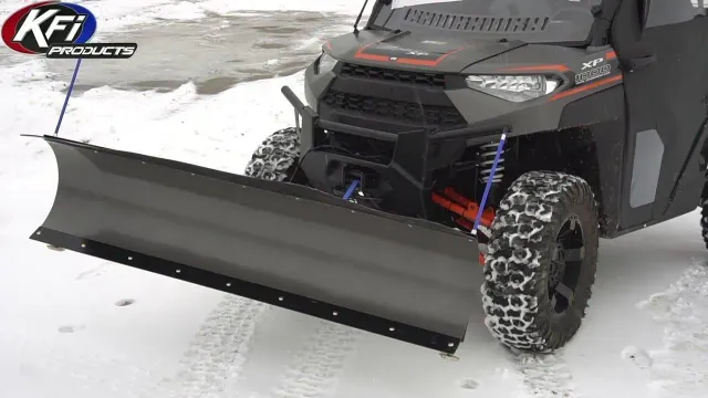 Black UTV with a gray snow plow blade clearing snow